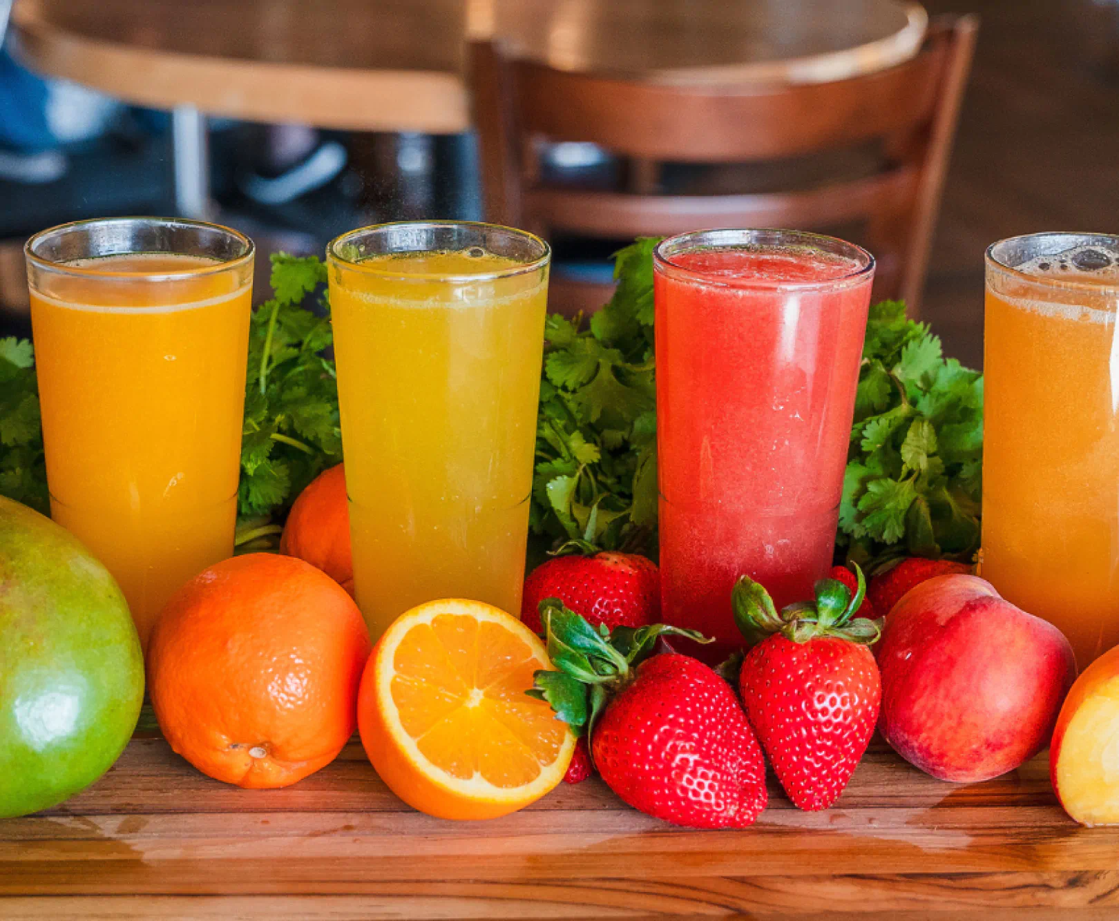 Colorful fruit juices sit in a line, surrounded by fresh berries and citrus.