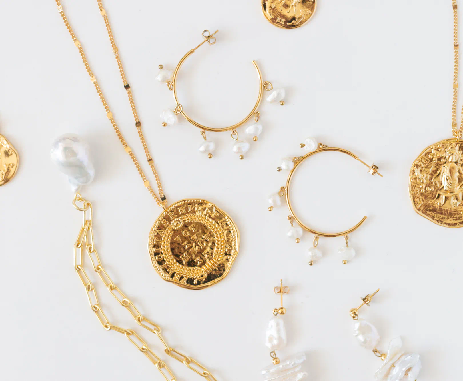 A collection of gold jewelry sit against a white backdrop.