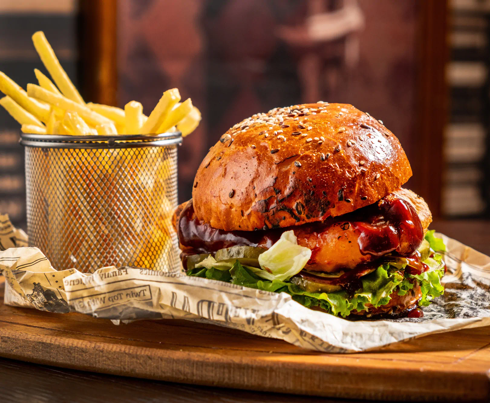 A large burger and fries sit on a wooden board.