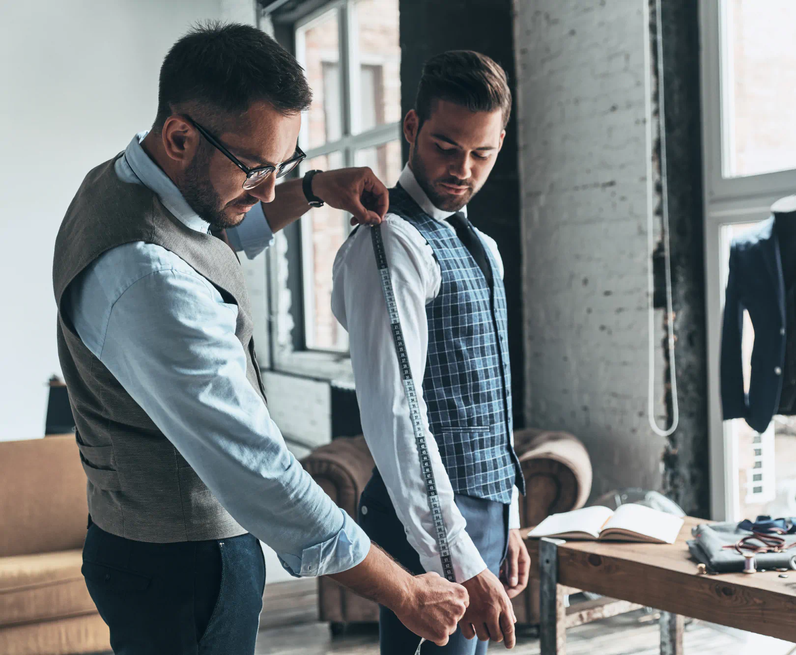 Man measuring another mans sleeve length while be fitted for a suit