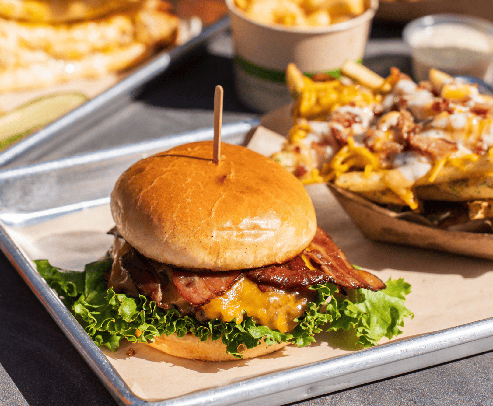 Bacon burger with fries sitting on metal tray