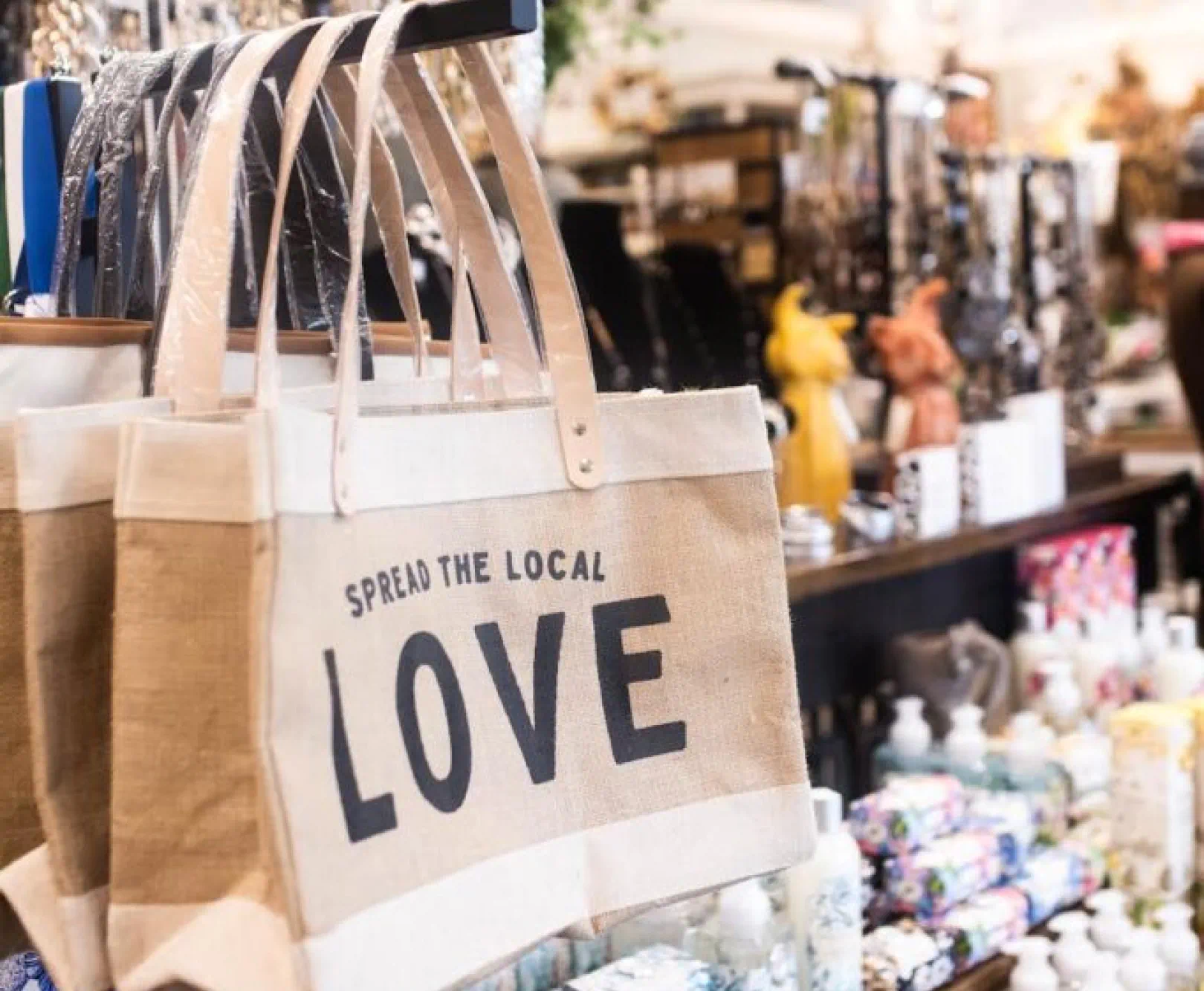 a display of canvas bags with the text "spread the local love" and various other products in the background