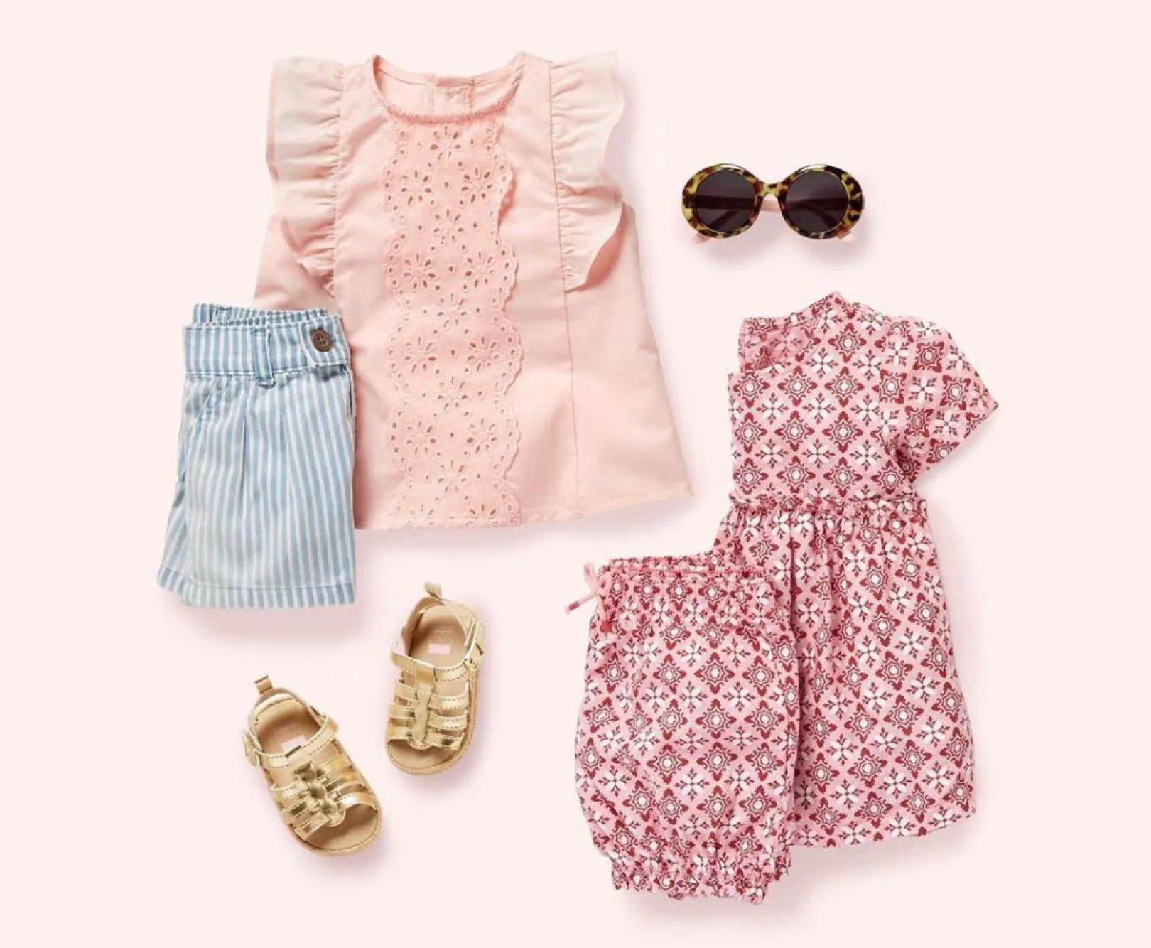 A collection of pink and blue children's clothing sit against a pink backdrop.